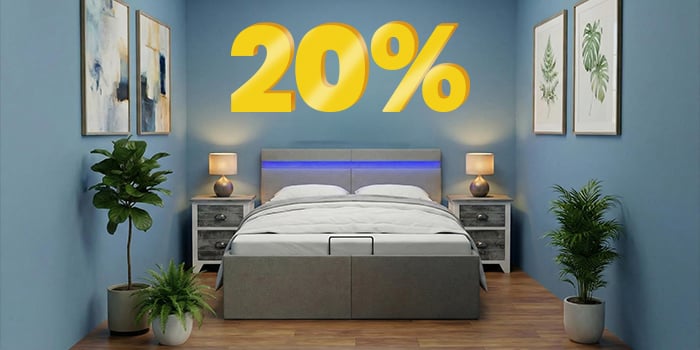 Reklaminis skydelis su „20 %“ nuolaida dideliais geltonais 3D skaičiais virš moderno miegamojo su pilka lova, mėlynomis sienomis ir augalais prie lovos. Spustelėkite ir peržiūrėkite kolekcijos prekes.