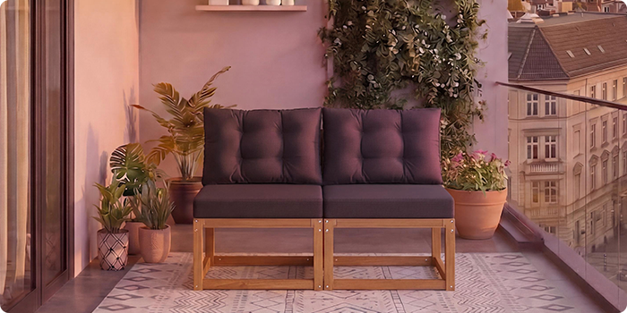 Dvivietė modulinė medinė sofa su tamsiai pilkomis pagalvėlėmis balkone, apsuptame vazoniniais augalais ir miesto vaizdu fone